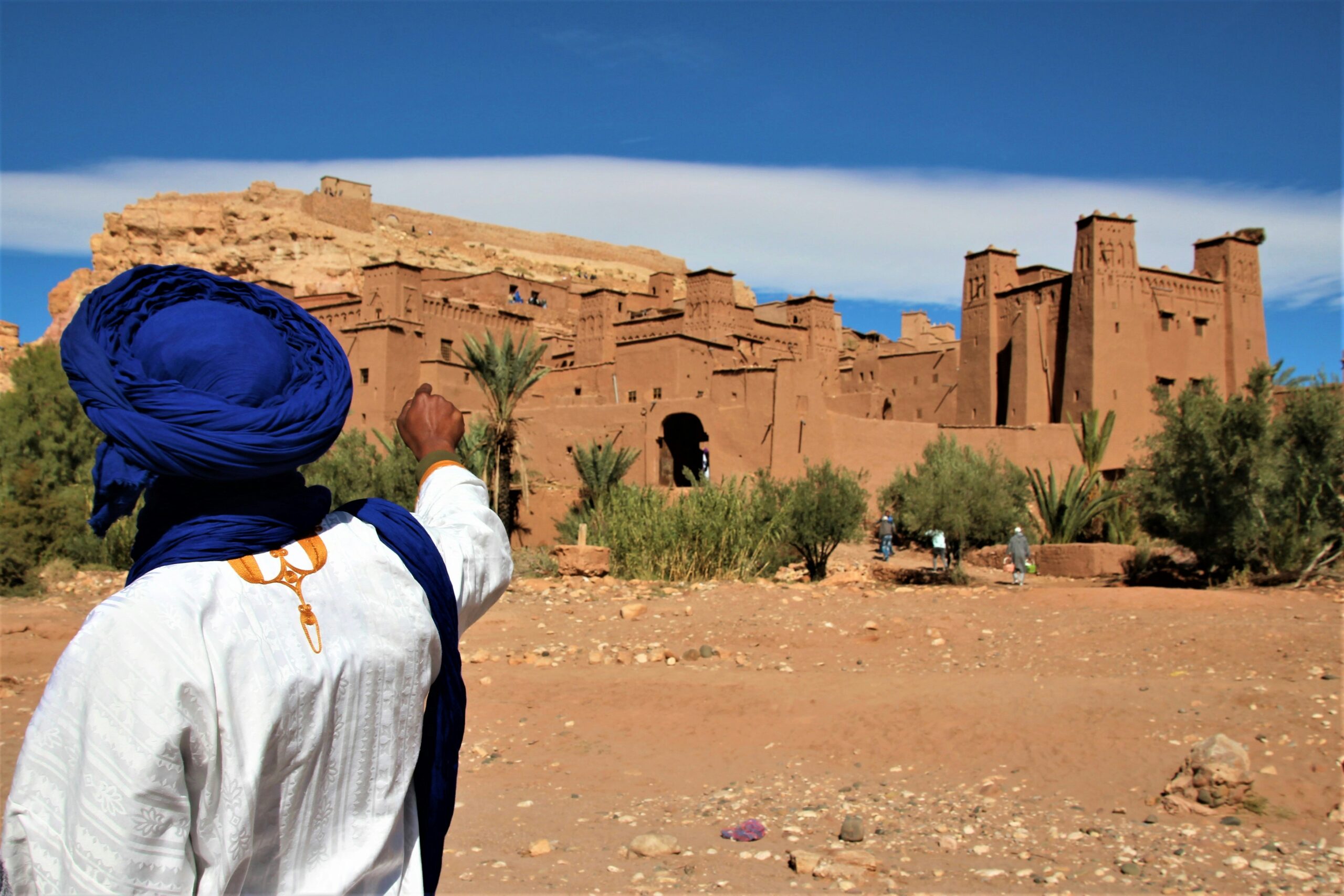 Traditional Berber guide pointing toward Ait Benhaddou fortified village near Ouarzazate Morocco